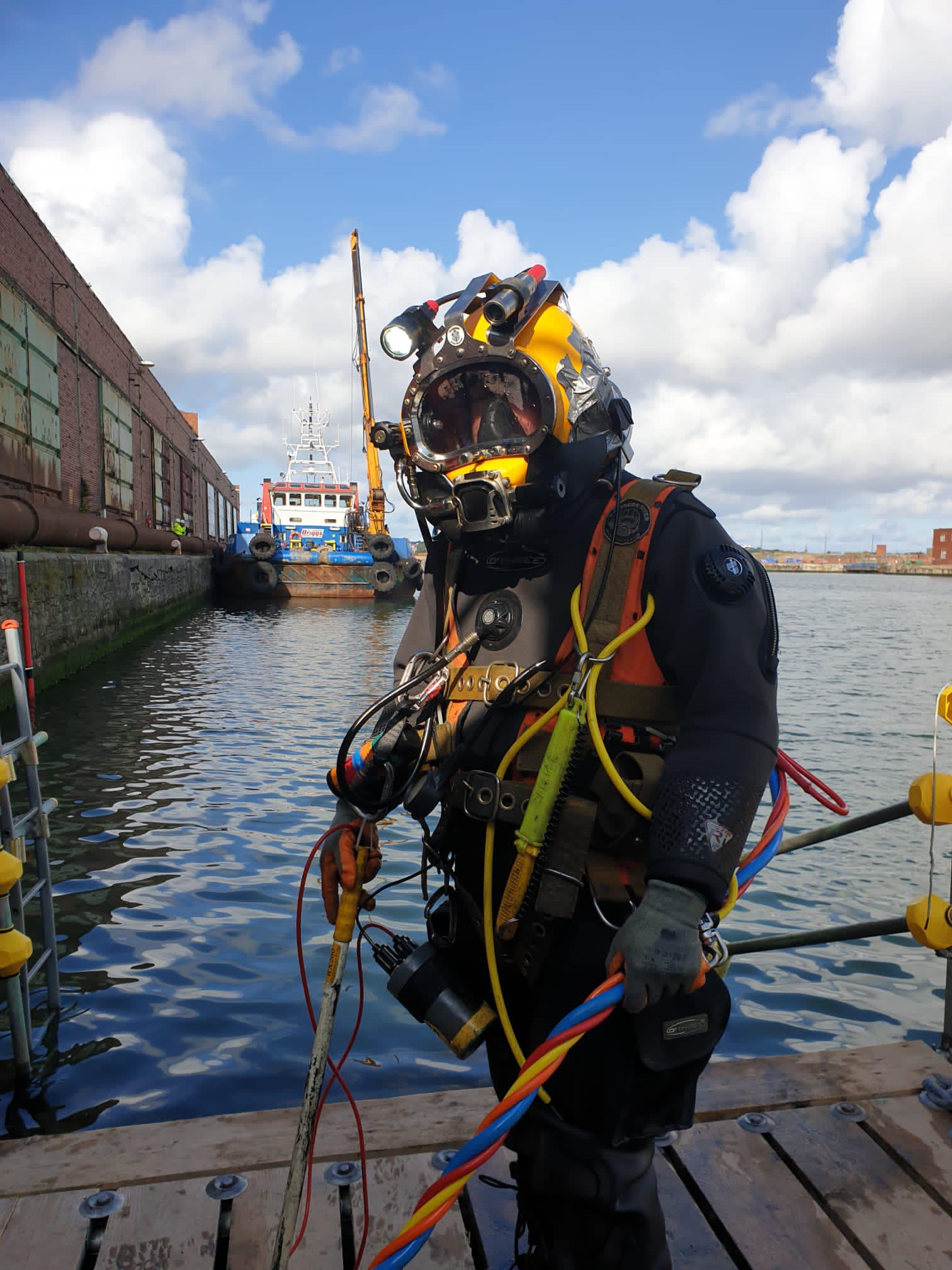 Commercial diver on a dock in the foreground of Bramley Moore Dock.