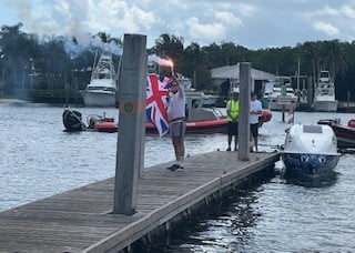 Man on a pier waving a union jack flag.