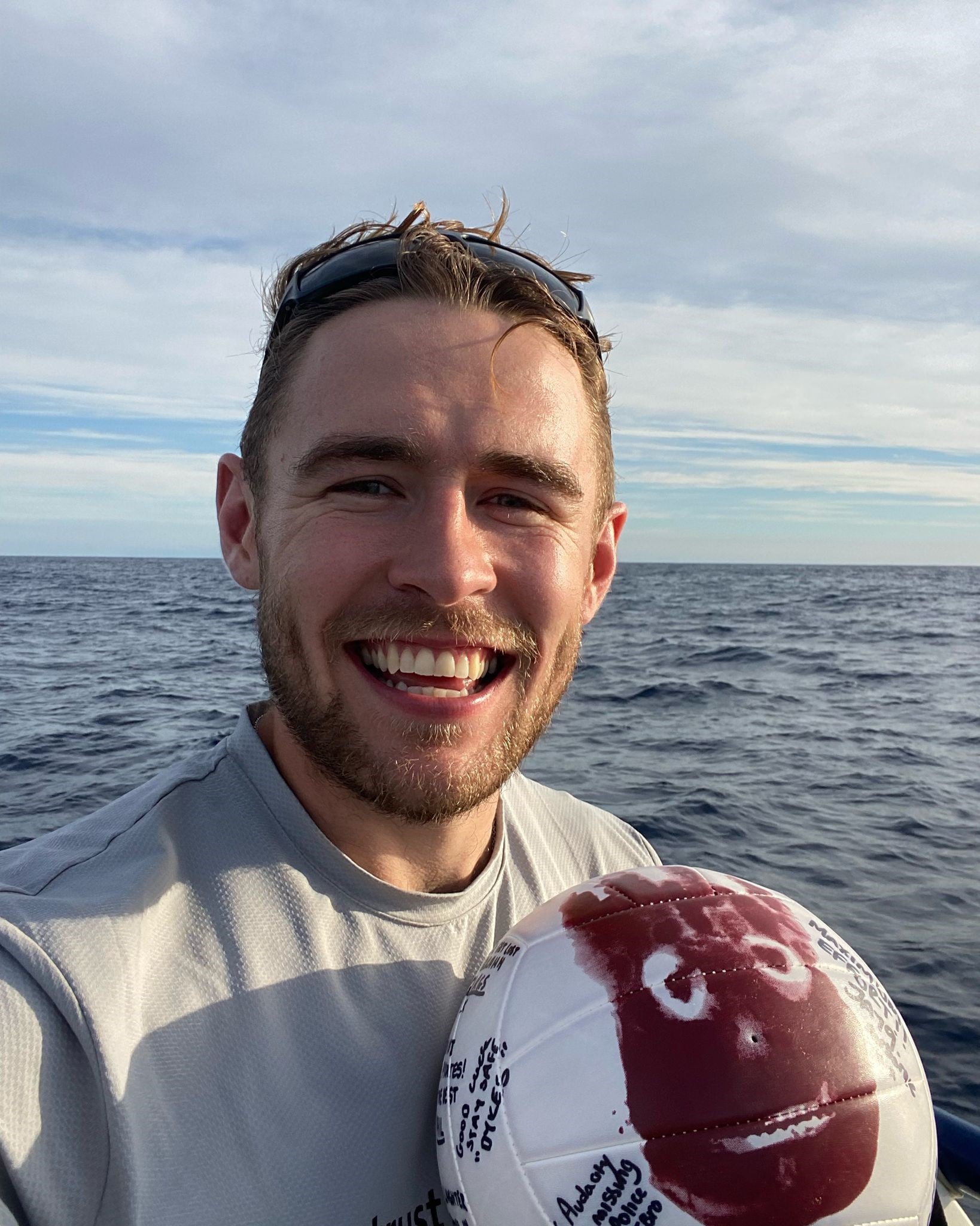 Smiling man at sea holding a Wilson football