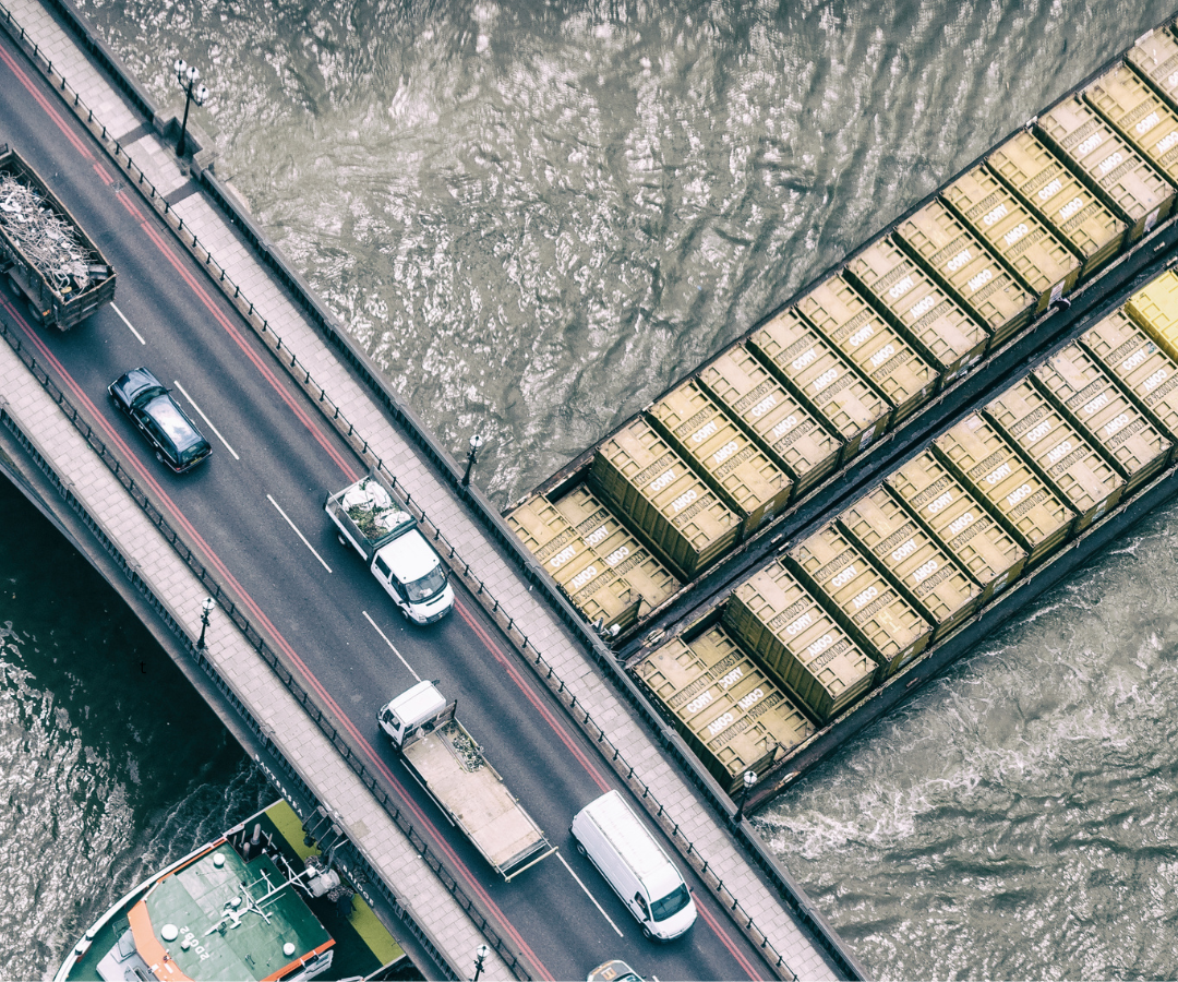 A cargo barge passing under a road bridge on the River Thames.